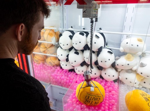 Player lining up a claw drop over panda plushies near the chute